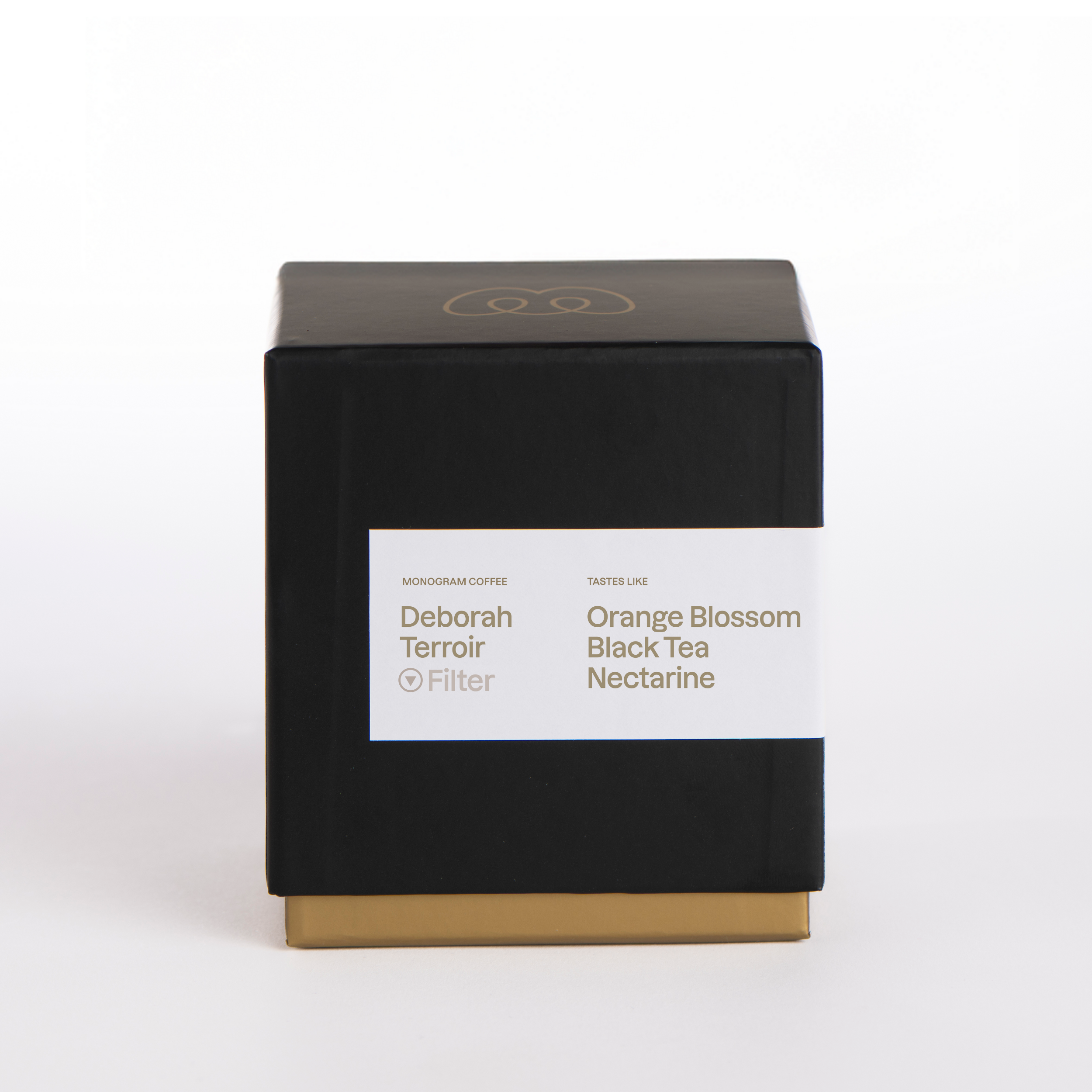 A premium black and gold box of Monogram Finca Deborah Terroir filter coffee, a washed Gesha from Panama with tasting notes of orange blossom, black tea, and nectarine.