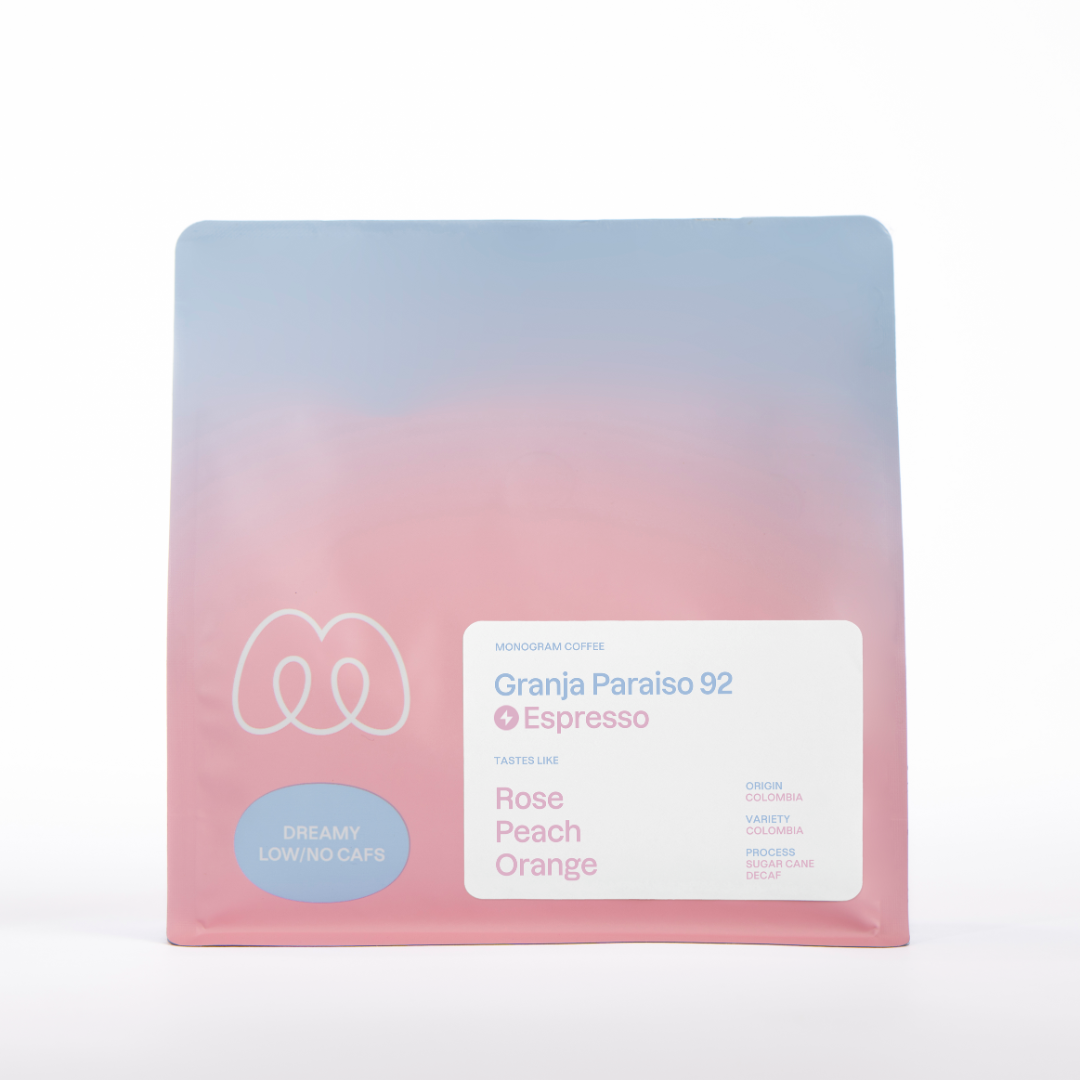 A blue and pink gradient bag of Monogram Granja Paraiso 92 espresso coffee, a Sugar Cane process decaf from Colombia with tasting notes of rose, peach, and orange