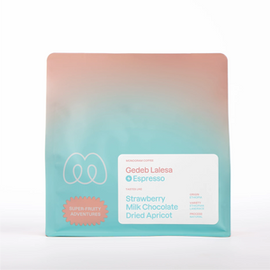 A teal and peach gradient bag of Monogram Gedeb Lalesa espresso coffee, a natural-processed Ethiopian Landrace variety from Gedeb, Ethiopia, with tasting notes of strawberry, milk chocolate, and dried apricot