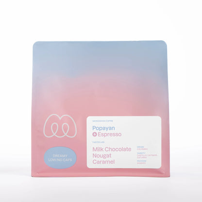 A blue and pink gradient bag of Monogram Popayan espresso coffee, a washed decaf from Colombia (Castillo, Catimor, and Caturra varieties) with tasting notes of milk chocolate, nougat, and caramel.
