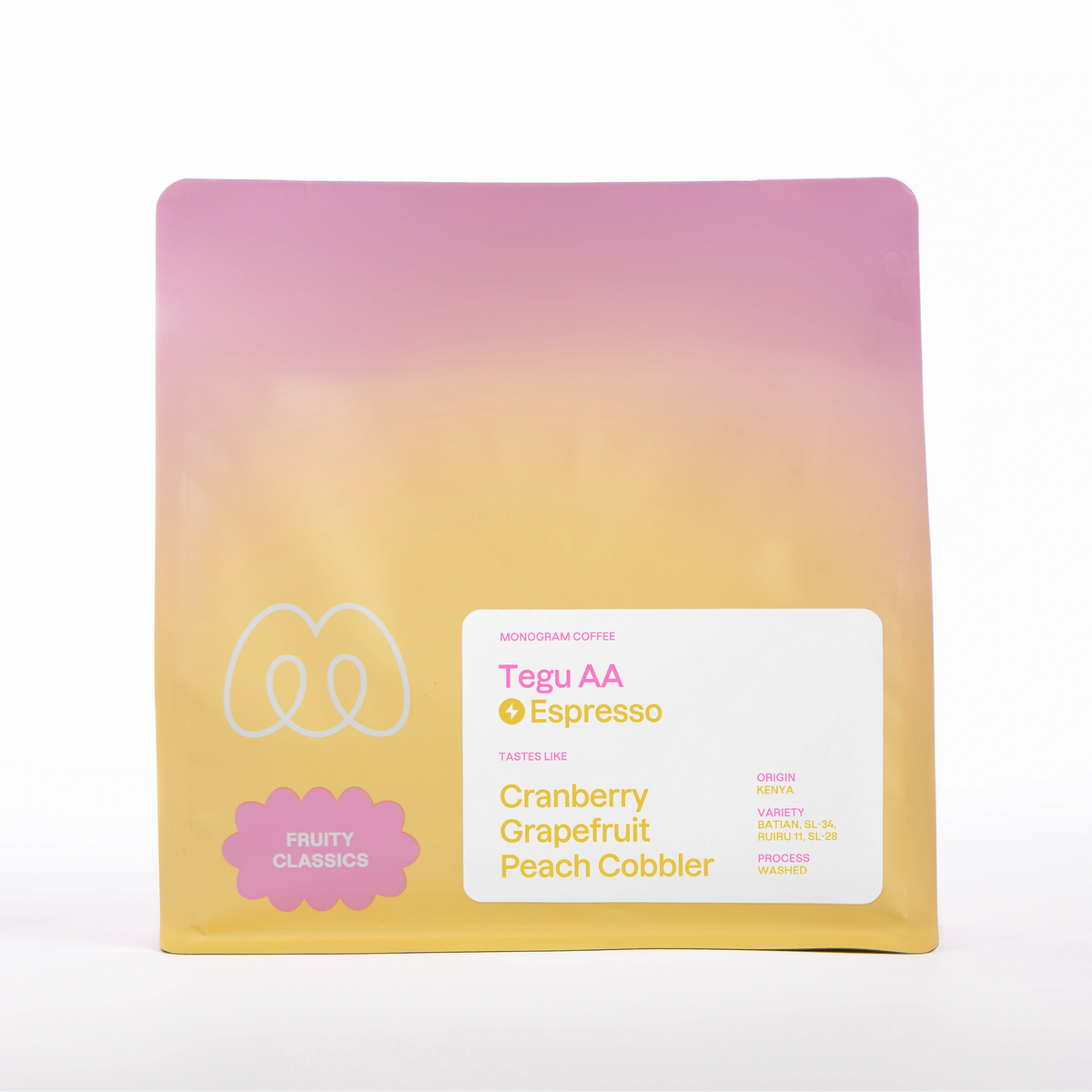 A pink, orange, and yellow pastel gradient bag of Monogram Tegu AA coffee, a washed processed blend of Batian, SL-34, Ruiru 11, and SL-28 varieties from Kenya with a Fruity Classics label badge and tasting notes of cranberry, grapefruit, and peach cobbler.